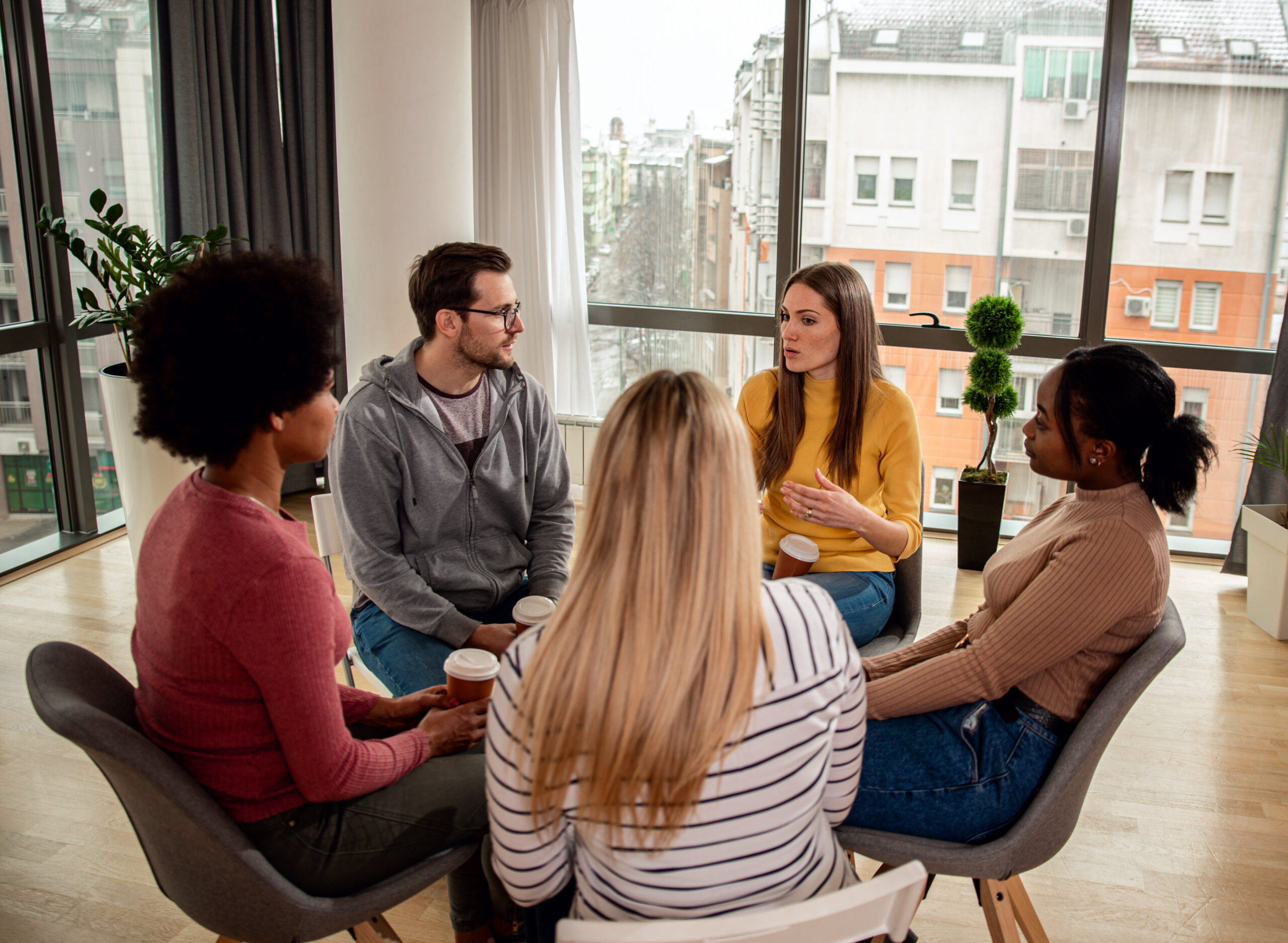 Diverse group of people sitting in a circle in a group.